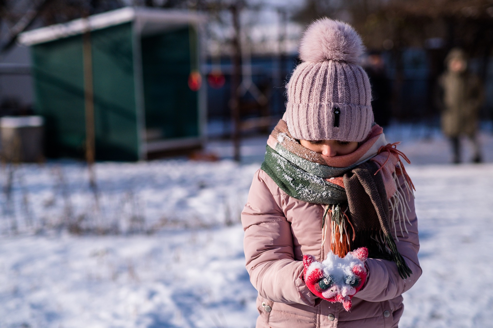 criança brincando na neve com roupa de frio